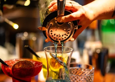 A bartender straining a freshly made cocktail into a glass.