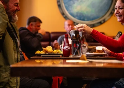 Guests laughing together over a meal of fish and chips.