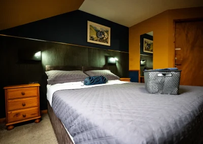 A hotel bedroom bedside table with a lamp beside a neatly made bed.