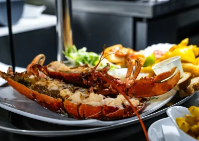 A whole cooked lobster split in half, served with battered fish, lemon and dips on the seafood platter.