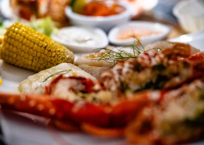 Close-up of grilled king scallops with fennel garnish, corn on the cob and lobster claw on the seafood platter.