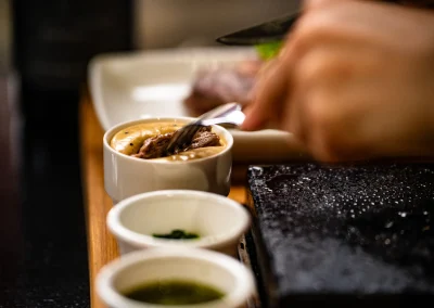 A piece of steak on a fork being dipped into peppercorn sauce.