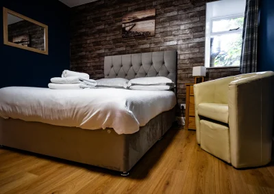 Double bedroom at Thorshaven Apartment with wooden flooring and a reading chair